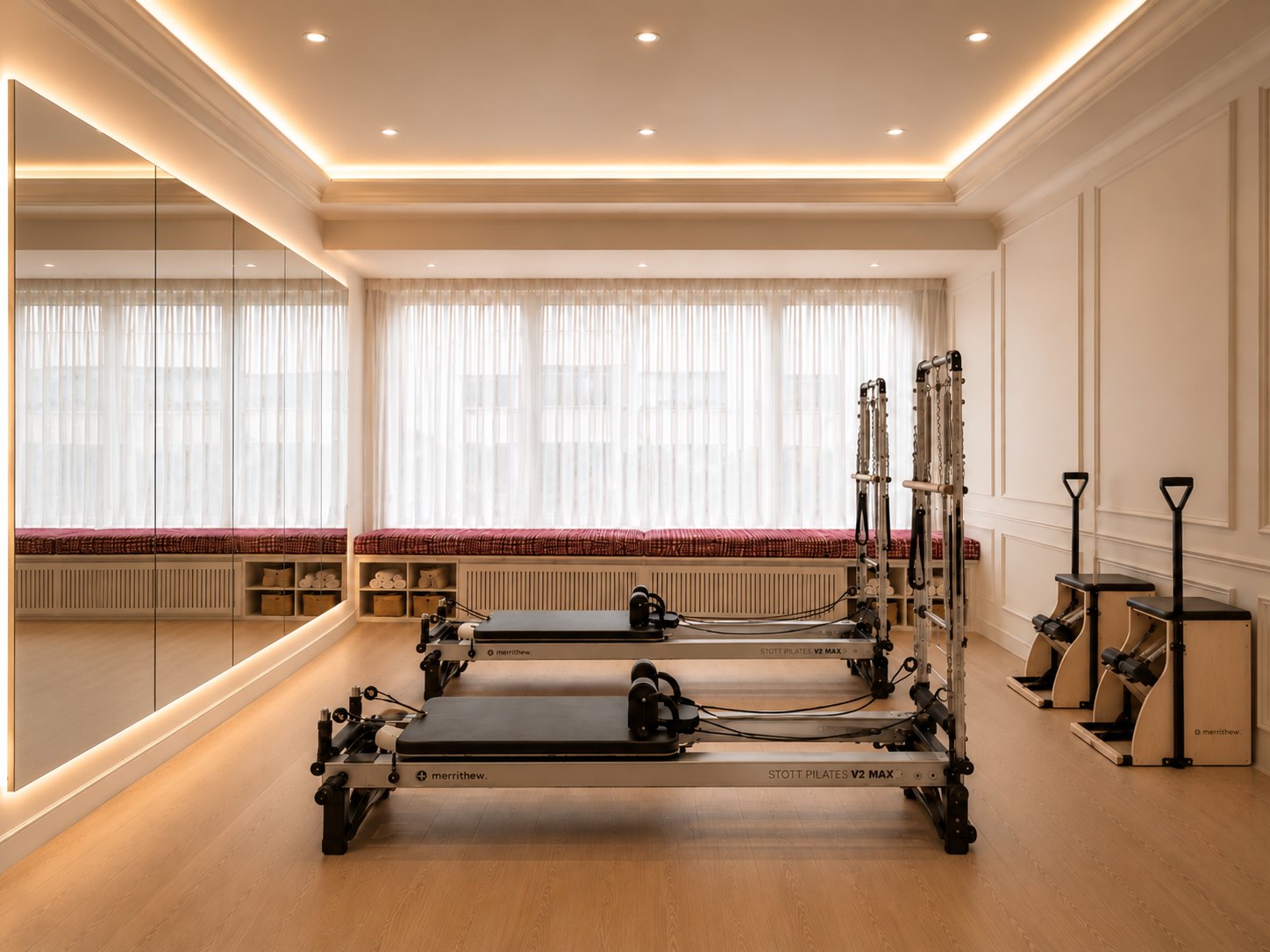 The Private Pilates Co. studio: a full-length backlit mirror wall, two Merrithew reformers, two Stability Chairs and a sheer-curtained window bench